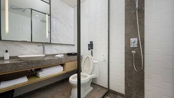 Un baño moderno con tocador de mármol, inodoro y zona de ducha.