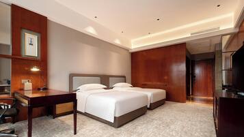 Habitación de hotel con dos camas, un escritorio, una silla, un espejo y un televisor.