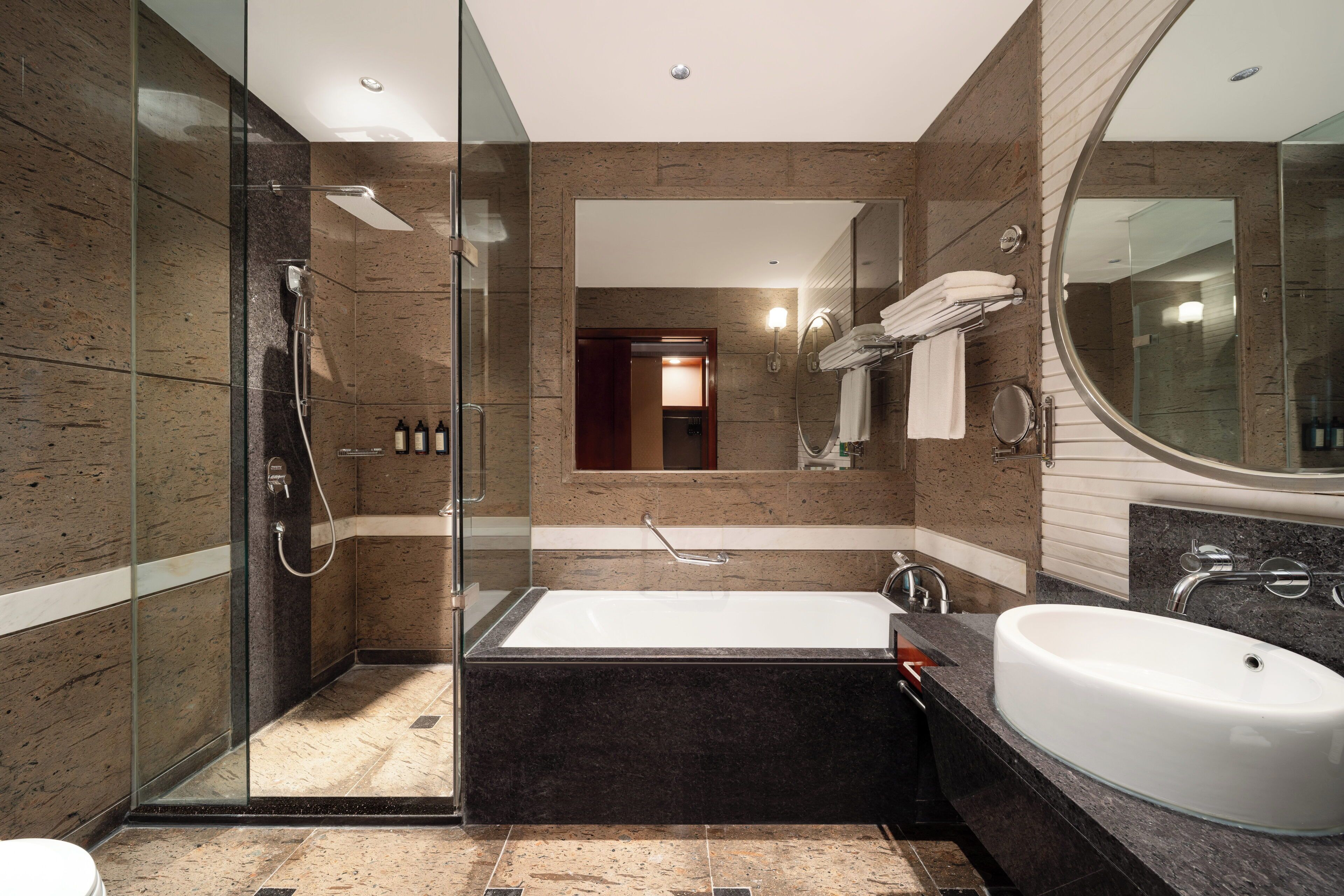 Un baño moderno con ducha envuelta en vidrio, una bañera independiente y un lavabo grande.