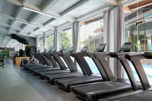 A row of stationary treadmills in a gym with large windows and a high ceiling. - Empark Grand Hotel Kunming (Kunming)