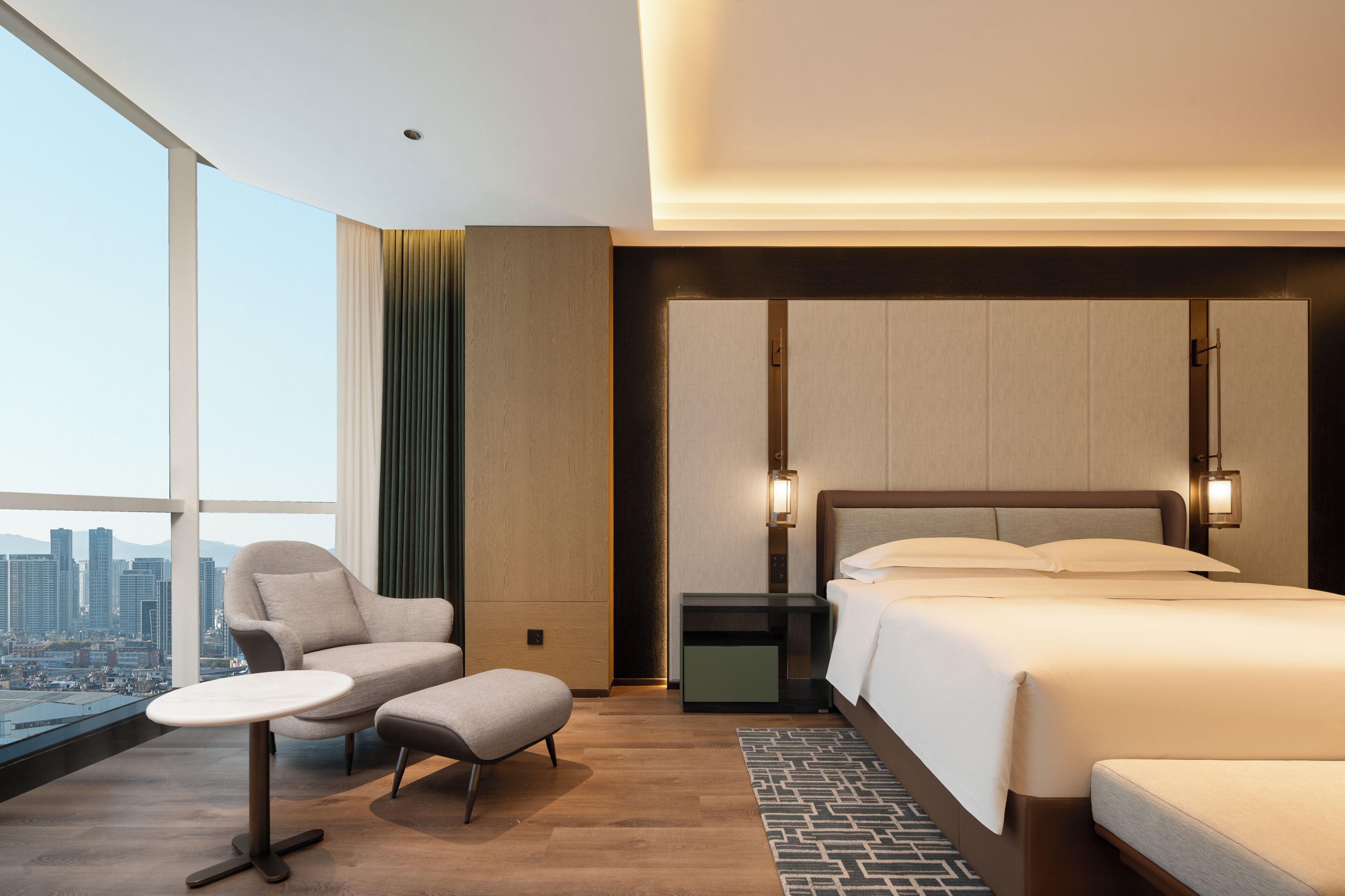 A hotel room with a large bed, a chair, a small table, and a nightstand.