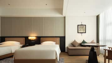 A hotel room with two beds, a sofa, a small table, and a picture on the wall.