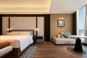 A modern hotel room with a large bed, a sitting area with a table, and a view of the city through the window. - Empark Grand Hotel Kunming (Kunming)