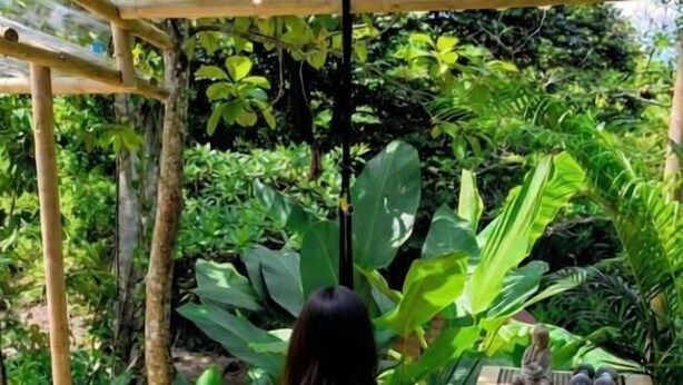 Una persona sentada sobre una esterilla de yoga al aire libre, con un paisaje natural de fondo.