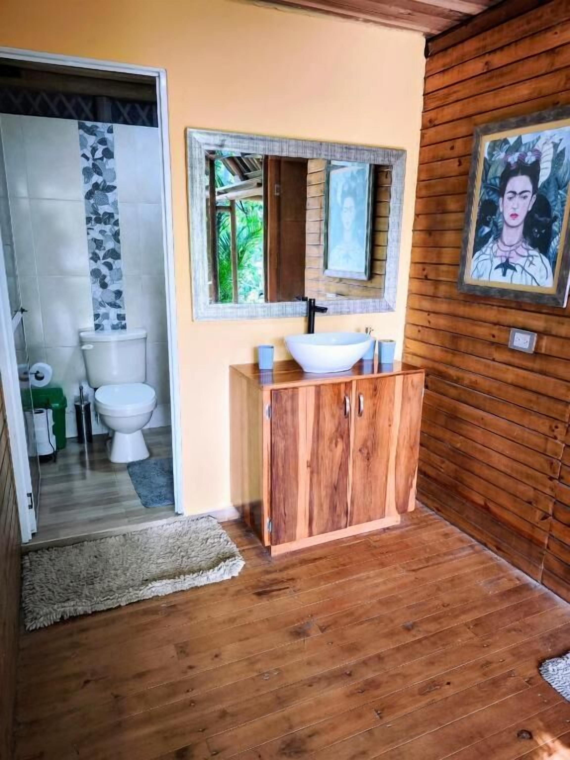 Un baño con tocador de madera, un lavabo blanco y un espejo encima.