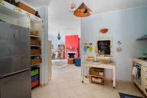 Eine moderne Küche mit Kühlschrank, ein Essbereich mit roter Wand und einem Kreidetafel-Schild.