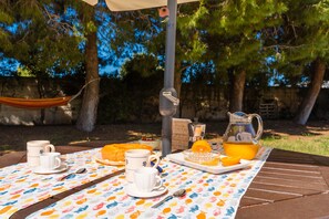 Ein Esstisch im Freien, gedeckt mit Frühstücksartikeln, eine Hängematte und eine Kaffeemaschine.