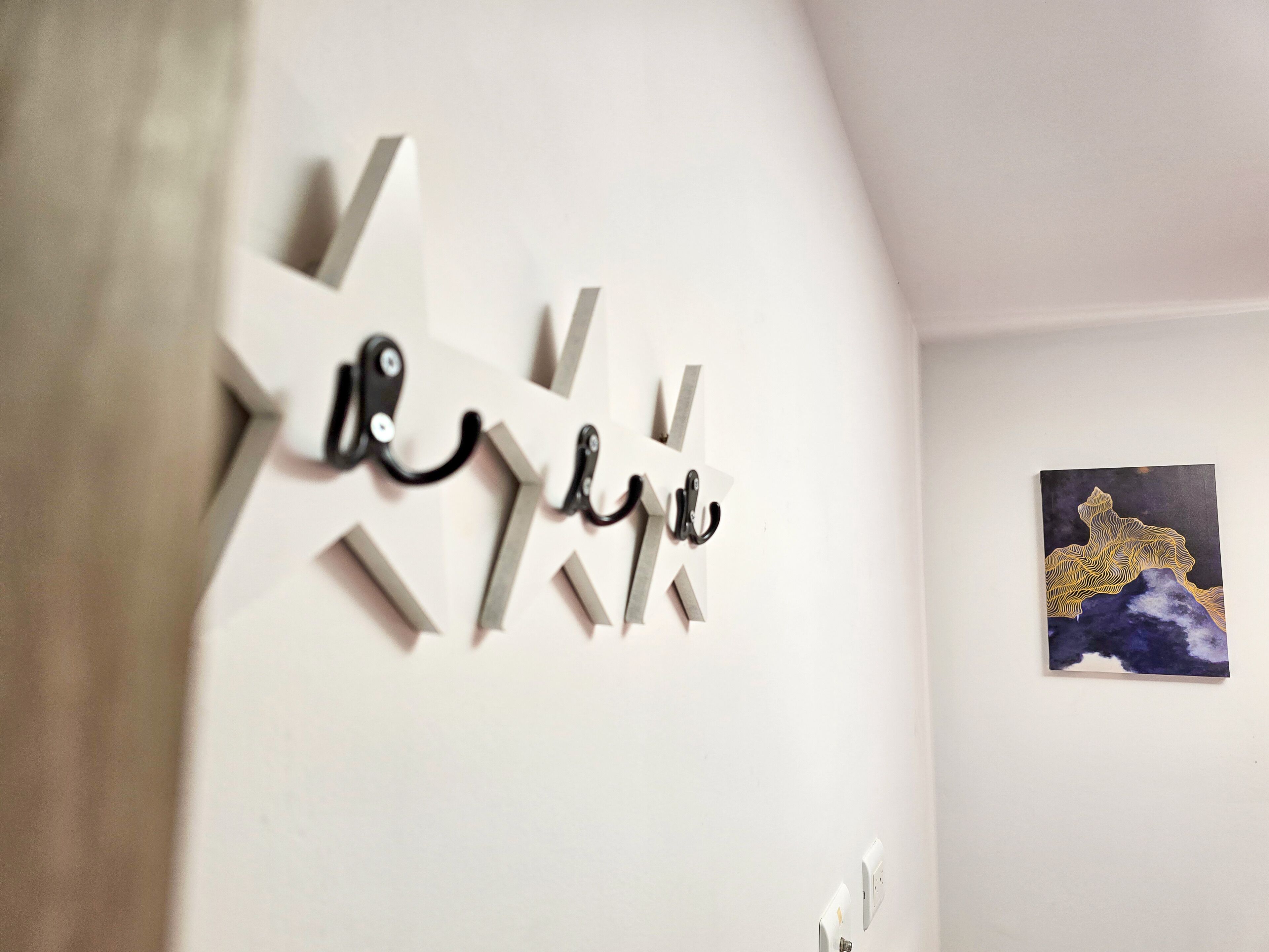 A wall with a geometric art piece and a framed picture.