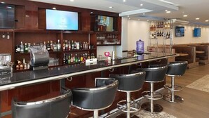 A bar area with a long counter, multiple stools, and a television screen. - Hotel Costa del Sur (Ilo)