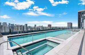 Ein Dachpool mit Blick auf eine Stadtlandschaft, umgeben von Hochhäusern.