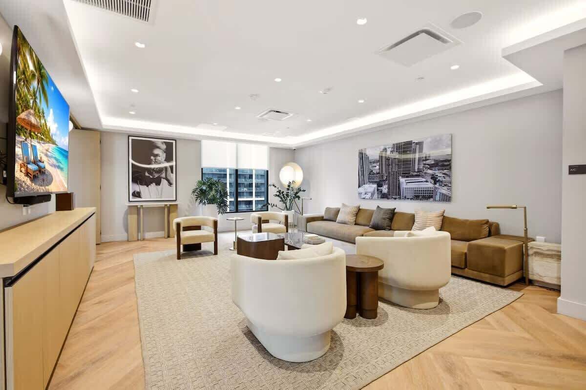 A modern living room with a sofa, armchairs, a coffee table, and a TV.