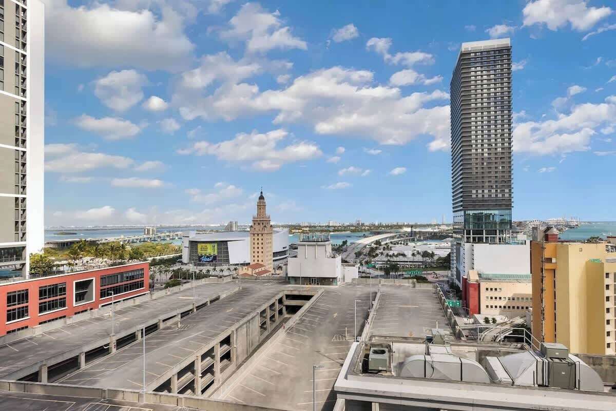 Un immeuble de grande hauteur au design moderne, un parking à plusieurs niveaux et une vue dégagée sur le paysage urbain environnant.