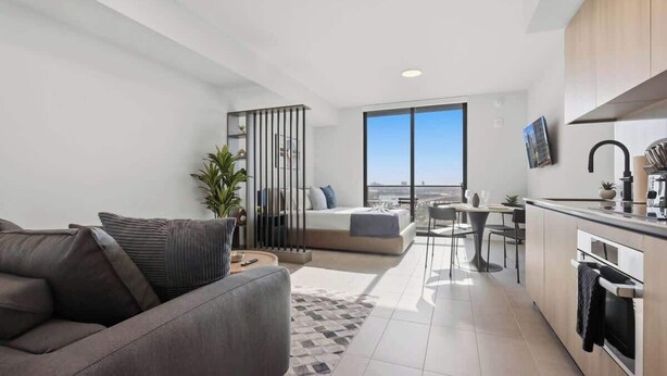 Un appartement moderne comprenant un espace de vie, une kitchenette et un balcon avec vue sur la ville.
