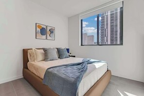 A modern bedroom with a large bed, a window with a city view, and abstract art on the wall. - Elegant 1 Bedroom | Premium Resort-Style Living (Miami)