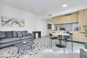 Una sala de estar moderna con sofá, mesa de centro y comedor con sillas.