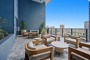 Ein moderner Balkon mit Sitzgelegenheit, Fernseher und Topfpflanzen.