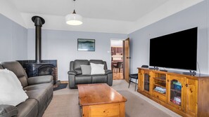 Ein Wohnzimmer mit Kamin, Ledersofa, Couchtisch aus Holz und Fernseher.
