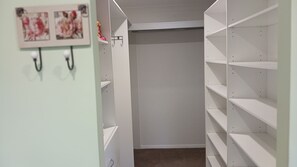 Ein begehbarer Kleiderschrank mit offenen Regalen auf der rechten Seite und einer verschlossenen Tür hinten.