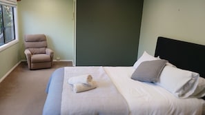 A bedroom with a bed, a chair, and a window. - Lamont House Bermagui - Lamont Street 104 (Bermagui)