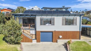 Ein modernes, zweistöckiges Haus mit einer überdachten Garage, Solaranlage und einer Treppe, die zu der oberen Etage führt.