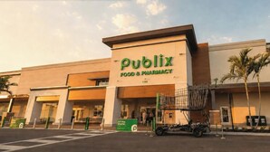 Een Publix Food & Pharmacy winkel met een groot bord, een parkeerplaats en een winkelwagen buiten.