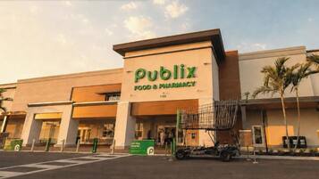 A Publix Food & Pharmacy store with a large sign, a parking lot, and a shopping cart outside.