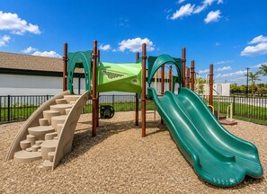A playground with a slide, climbing steps, and a green climbing structure. - 2BR Luxury North Retreat with Pool and Gym (Naples)
