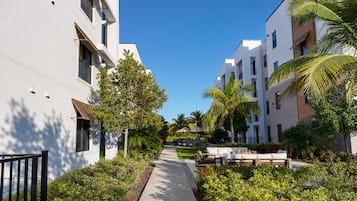 Un sendero bordeado por edificios modernos con balcones, rodeado de vegetación y palmeras.