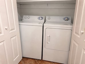 A laundry room with two front-loading washing machines and a dryer.