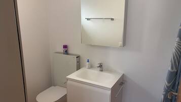 Une petite salle de bain propre, équipée de toilettes, d’un lavabo et d’un miroir.