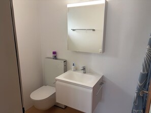 Ein kleines, sauberes Badezimmer mit Toilette, Waschbecken und Spiegel.