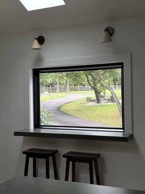 A room with a large window, two stools, and a wall-mounted light fixture.