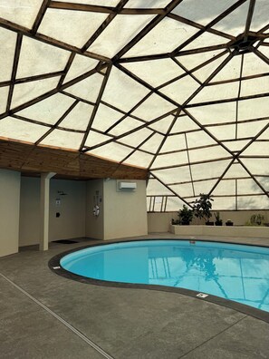 Ein Hallenbad mit Glasdecke, umgeben von Wänden und einem Betonboden.