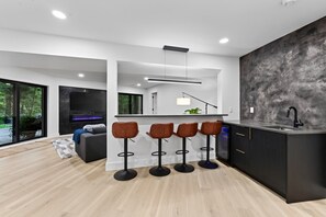 A modern kitchen with a bar area, a built-in oven, and a large window. - Carob Estate - Dome Covered Pool, Spa, & Natural Spring on 30 private acres! (Clever)