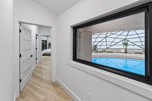 A modern interior with a large window overlooking a swimming pool.