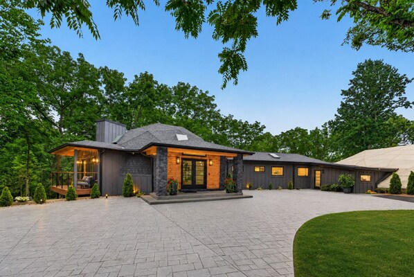 A modern house with a covered porch, a large driveway, and a well-maintained lawn.