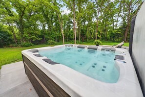 Un bain à remous doté d’une structure en bois, entouré d’une pelouse et d’arbres.