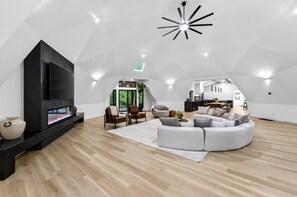 A modern interior with a fireplace, seating area, and a kitchen visible through an archway. - Carob Estate - Dome Covered Pool, Spa, & Natural Spring on 30 private acres! (Clever)