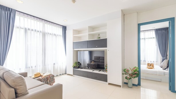 A modern living room with a sofa, a flat-screen TV, and a dining area with a table and chairs. - The Regent Kamala Condominium by PSR (Tambon Kamala)