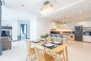 A modern kitchen with a central island, built-in appliances, and pendant lighting. - The Regent Kamala Condominium by PSR (Tambon Kamala)