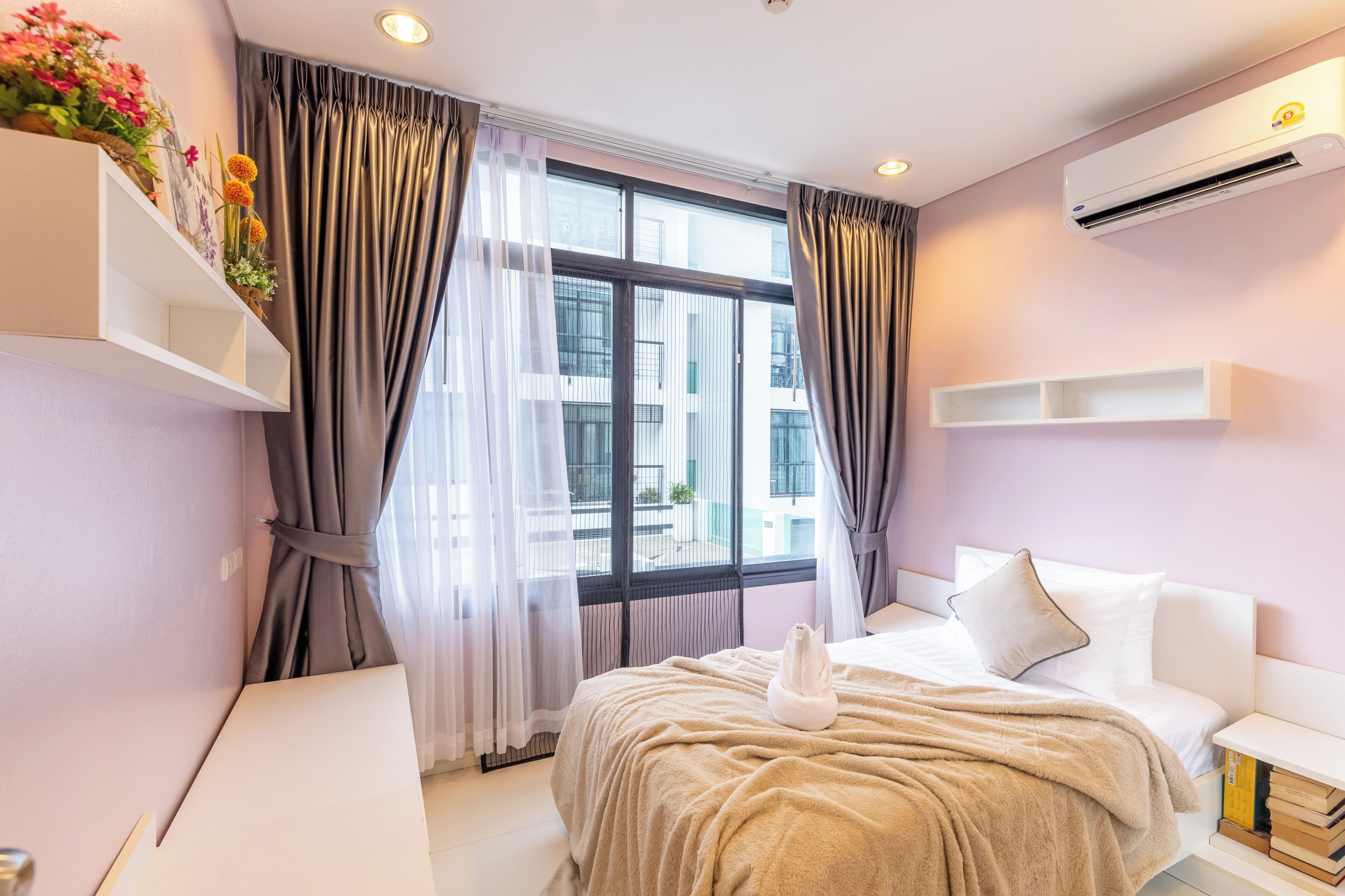 A modern hotel room with a bed, bedside tables, a desk, and a window with curtains.