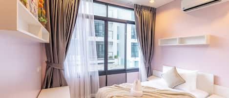 Quarto de hotel moderno com cama, mesas de cabeceira, escrivaninha e janela com cortinas.