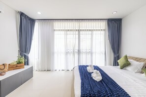 Un dormitorio moderno con cama, cortinas, una mesita de noche y una ventana.