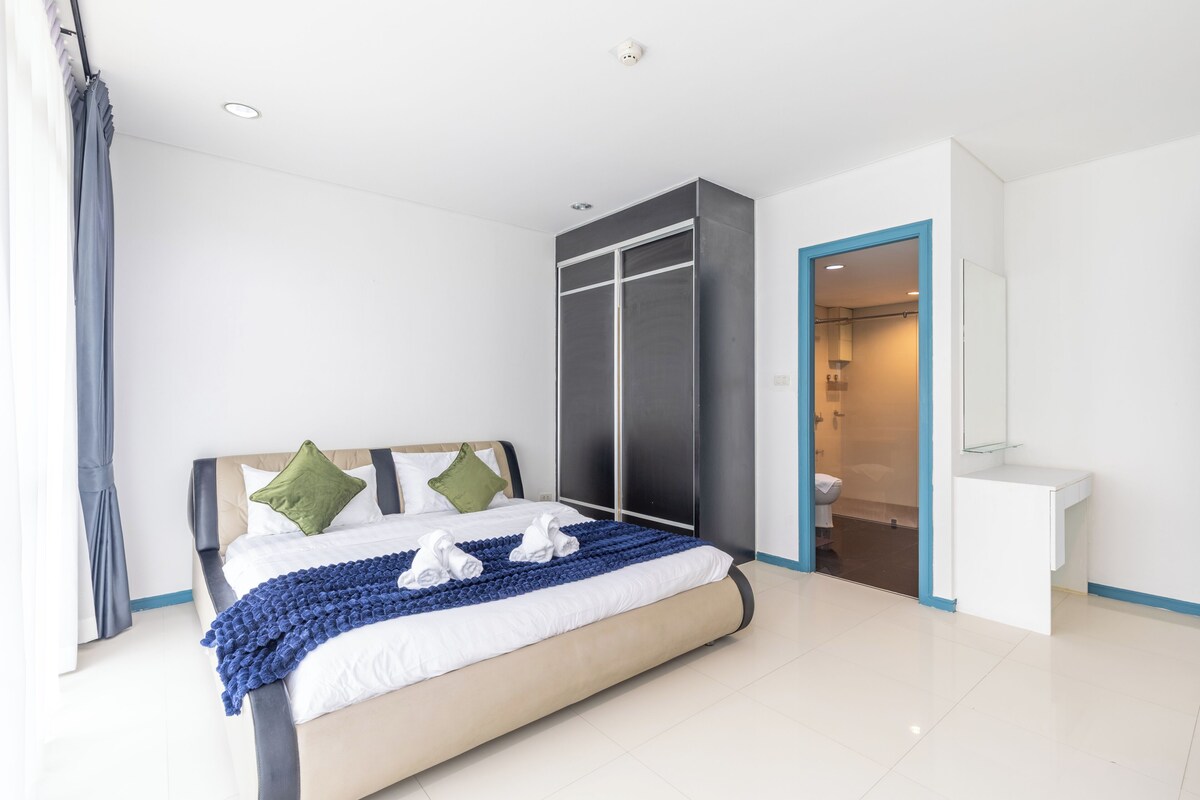 A modern bedroom with a bed, a wardrobe, and a bathroom.