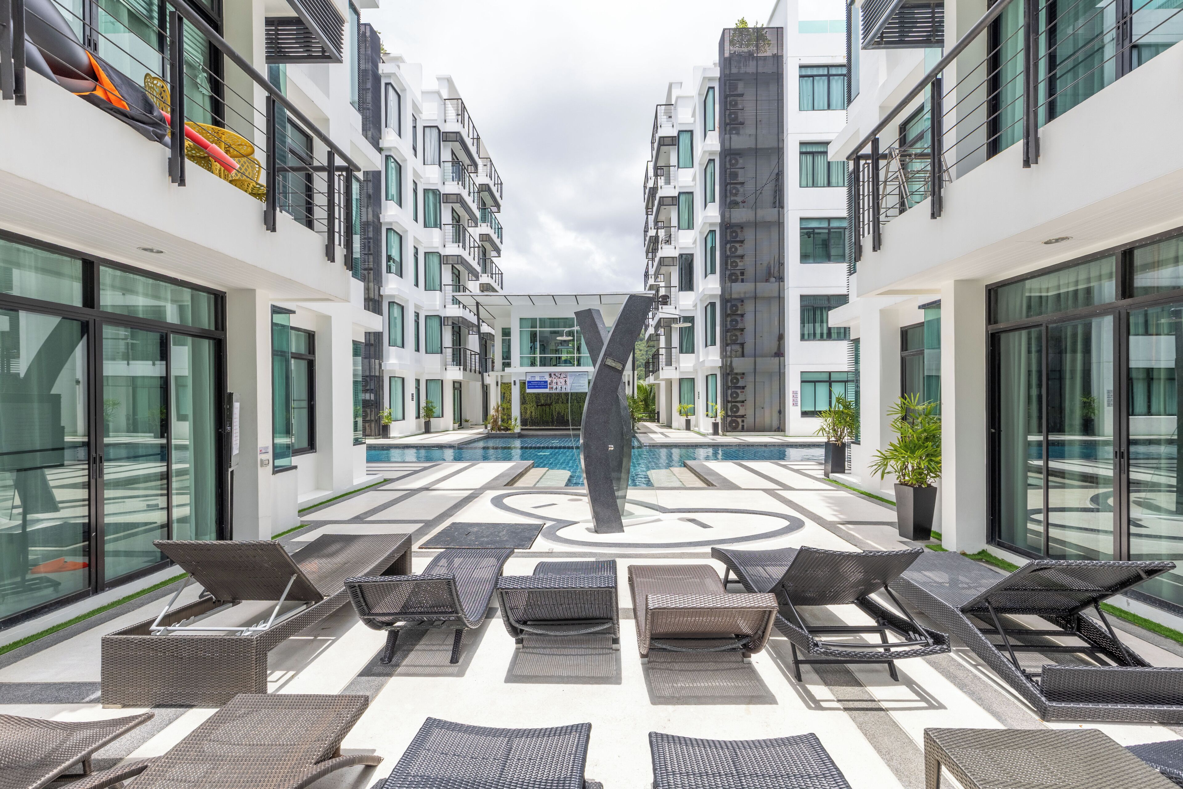 A modern hotel atrium with a central pool, lounge chairs, and a geometric floor pattern.