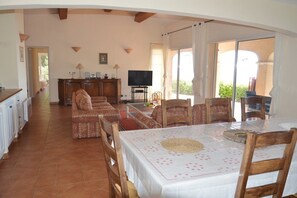 A dining area with a table set for four, a television, and a view of the outdoors. - Belle Villa 4 chambres à Gigaro avec vue mer (LA CROIX VALMER)
