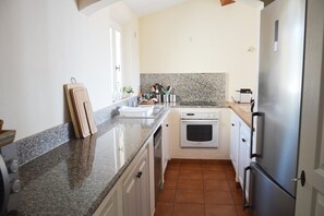 A kitchen with granite countertops, a built-in oven, a stainless steel refrigerator, and white cabinetry. - Belle Villa 4 chambres à Gigaro avec vue mer (LA CROIX VALMER)
