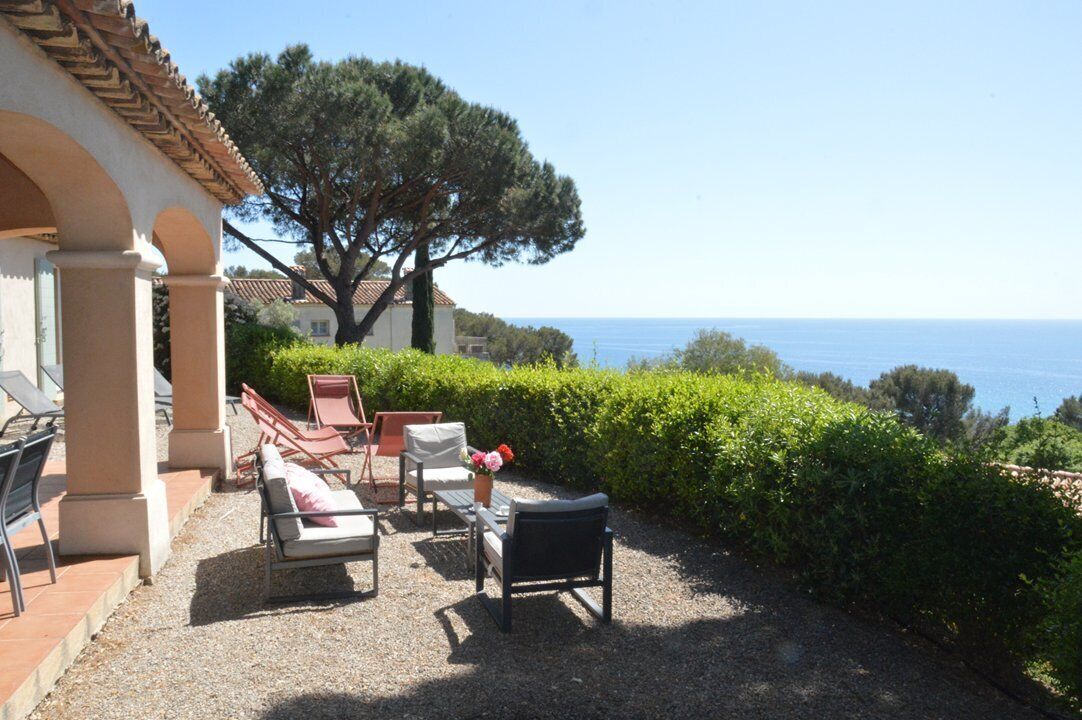 An outdoor seating area with chairs and a table, overlooking a coastal landscape.