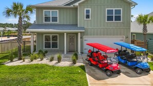 Ein zweigeschossiges Haus mit Garage und überdachter Veranda, vor der zwei Golfcarts geparkt sind.