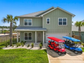 A two-story house with a garage, a covered porch, and two golf carts parked in front. - Windmark Coastal Paradise 5BR/5BA, private Pool, sleeps 18, pet friendly, 2 golf carts (Port St. Joe)